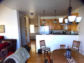 A kitchen with wooden cabinets, a central island, and pendant lighting. - Anemone Townhome 3 Bed 3 Bath (Dillon)