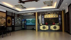 A reception area with a traditional design, featuring a reception desk, framed pictures, and a mural on the wall. - Li River (Guilin)