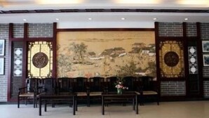 A traditional-style room with a large mural, wooden furniture, and decorative elements. - Li River (Guilin)