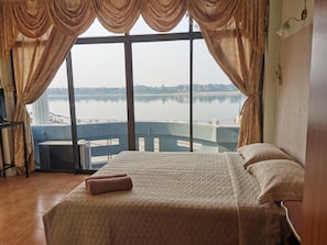 Una habitación con cama, cortinas y vistas a un lago.