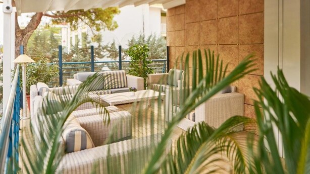 Un espacio al aire libre cubierto con mobiliario de mimbre y plantas en macetas.
