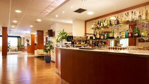 Una zona de bar con mostrador de madera, estantes llenos de botellas de licor y una máquina de café.
