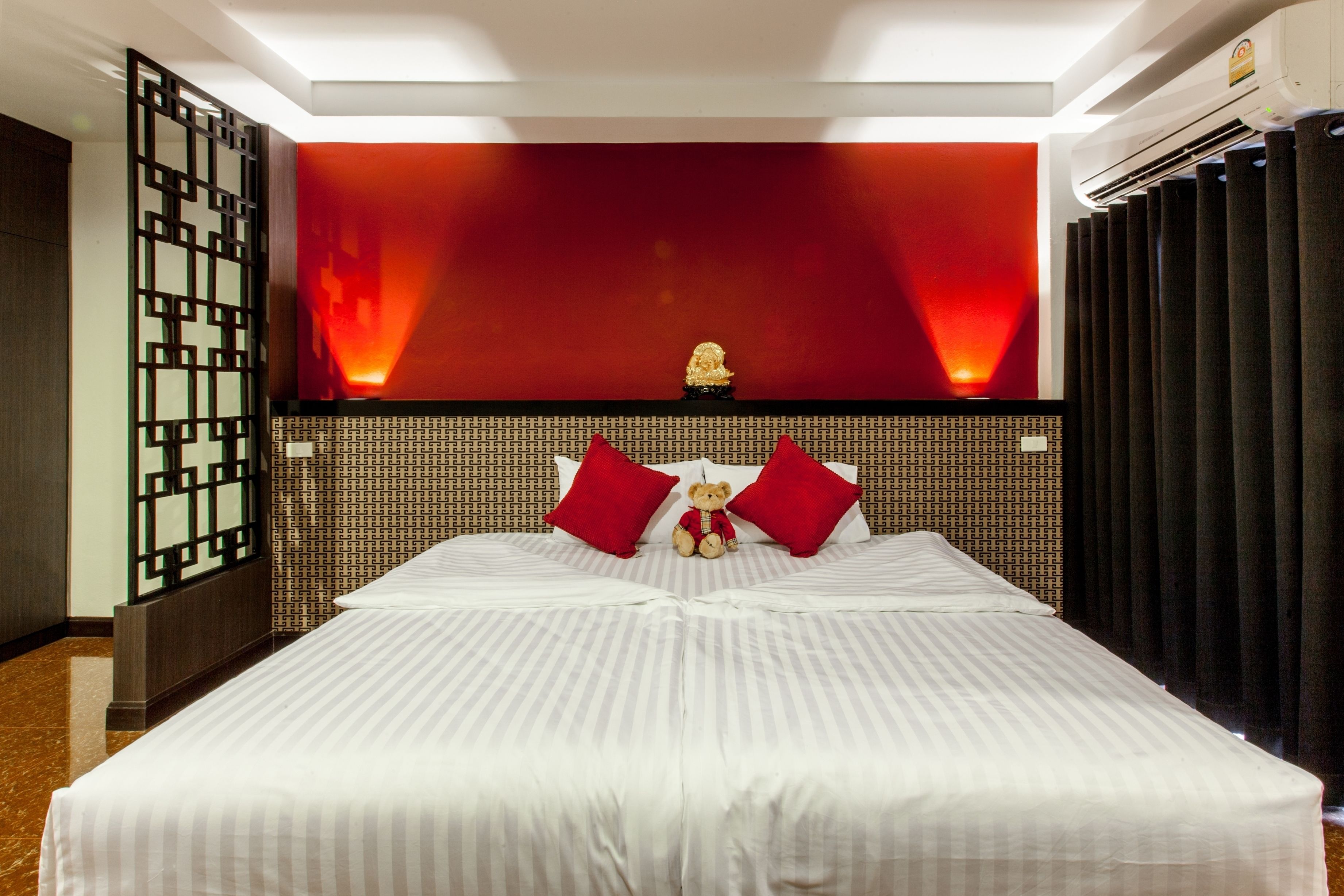 Camera d'albergo con un letto grande, un pannello decorativo e una piccola statua.