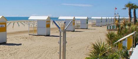 Beach huts with a sandy beach and the sea in the background.