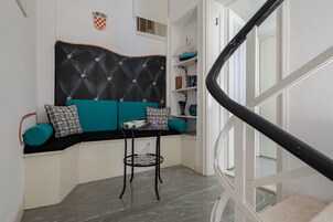 A corner seating area with a tufted headboard sofa, a small table, and a chair.