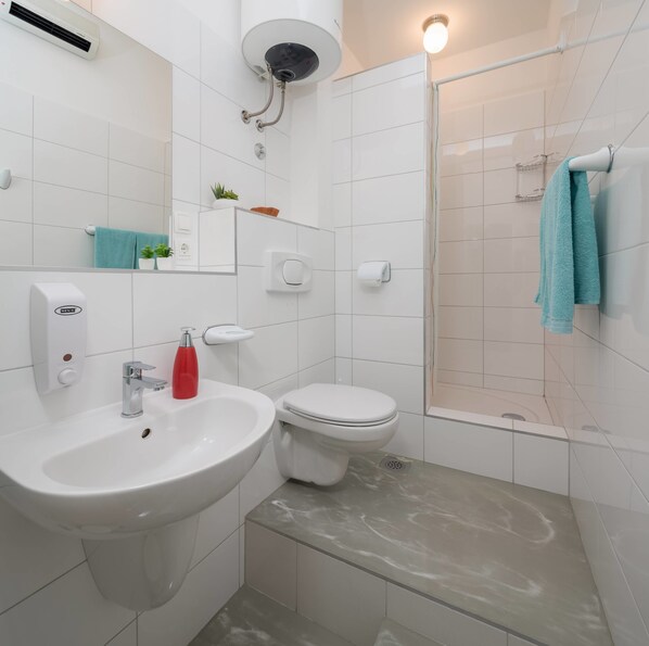A modern bathroom with a sink, toilet, and shower.