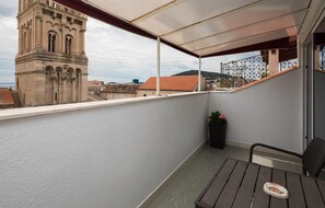 A balcony with a view of a historic tower, a small table, and a chair. - PLR Accommodation (Split)
