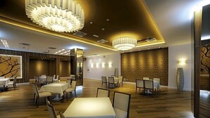 A modern dining area with multiple tables and chairs, recessed lighting, and decorative wall panels.