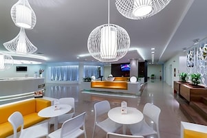 A modern hotel lobby with a reception desk, seating area, and decorative lighting.