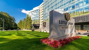 A hotel entrance with a sign reading 'LOTUS THERM SPA & LUXURY RESORT'.