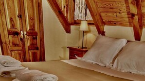Una camera d'albergo con soffitto in legno, un letto con lenzuola bianche e un comodino con una lampada.