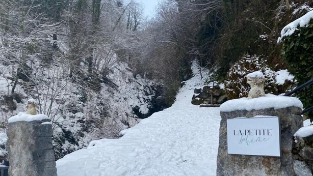 Un sentiero innevato che conduce a un cancello in pietra con un cartello che riporta la scritta "LA PETITE".