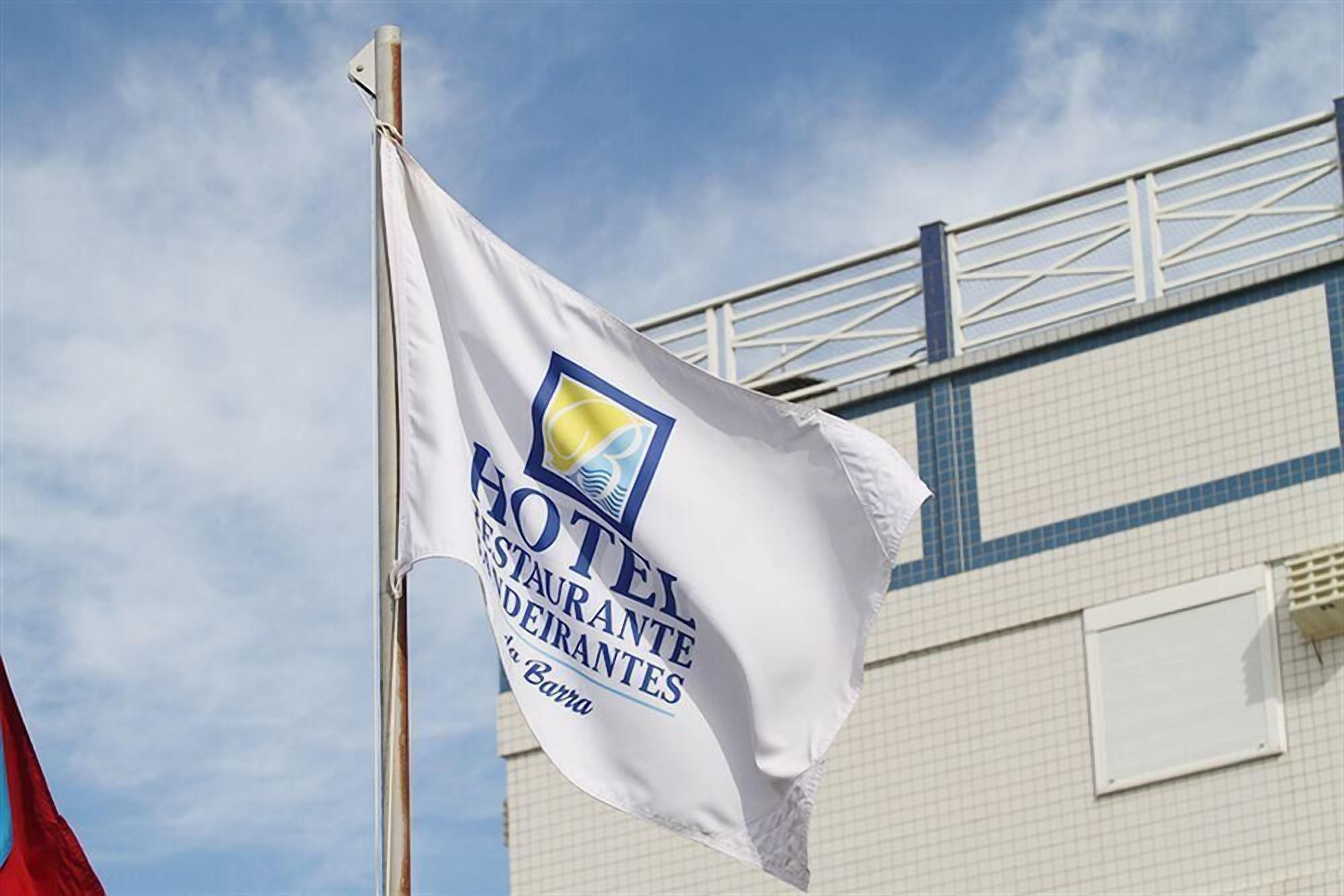 A flag with the text "HOTEL RESTAURANTE DEIRANTES" and a logo, mounted on a flagpole.