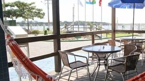 A covered outdoor seating area with tables and chairs, a hammock, and flags in the background. - Hotel Bandeirantes (Balneario Barra do Sul)