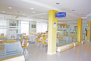 A hotel restaurant area with tables and chairs, a sign indicating a restaurant, and a glass display case. - Hotel Bandeirantes (Balneario Barra do Sul)