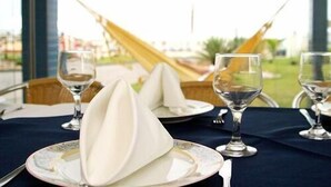 A dining table with white napkins, wine glasses, and plates set for a meal. - Hotel Bandeirantes (Balneario Barra do Sul)