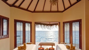 Ein Zimmer mit zwei Betten, einer Sitzbank und Blick auf das Meer.