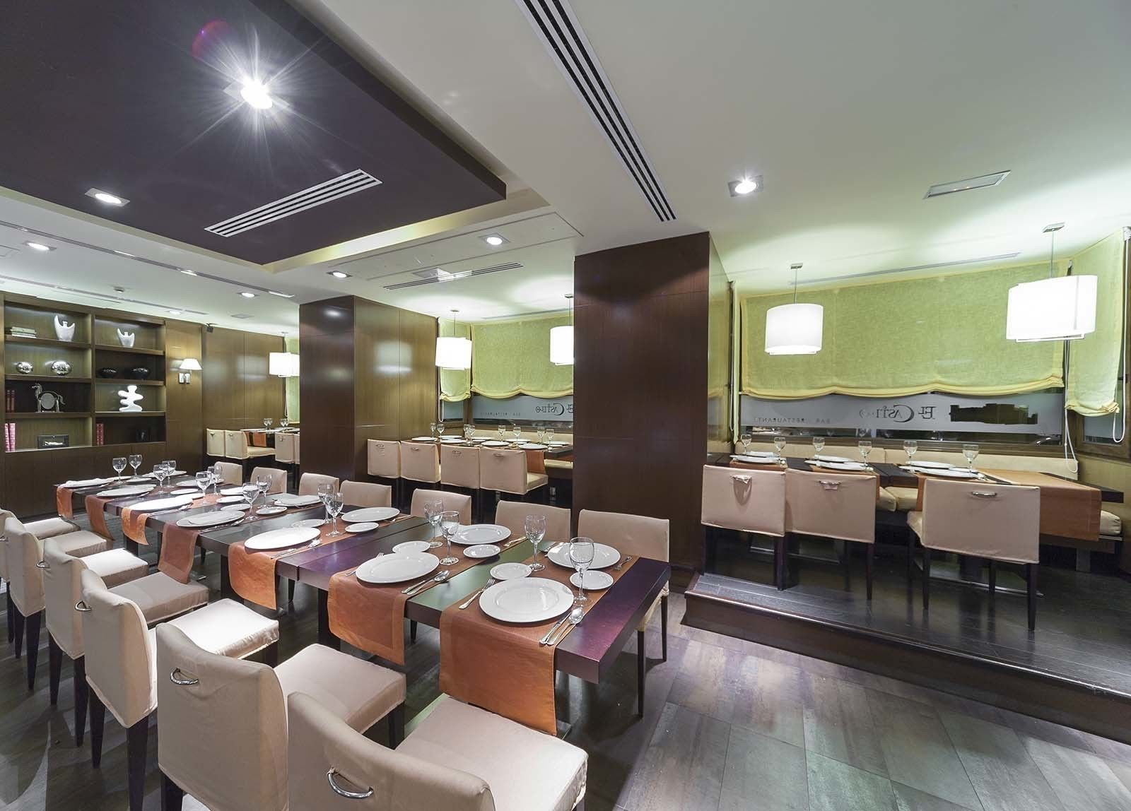 Un restaurante moderno con varias mesas, cada una dispuesta con platos, cubiertos y vasos.