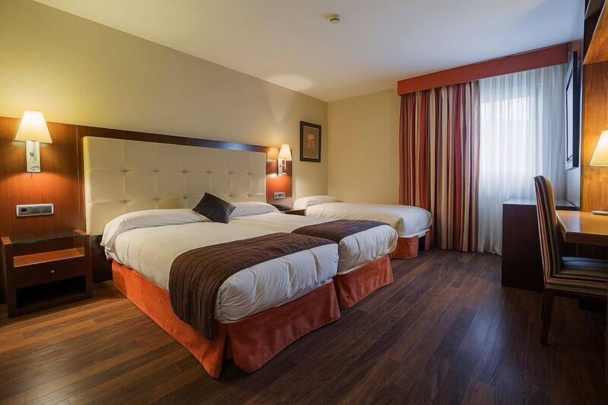 Une chambre d’hôtel avec deux lits, un bureau et une chaise.