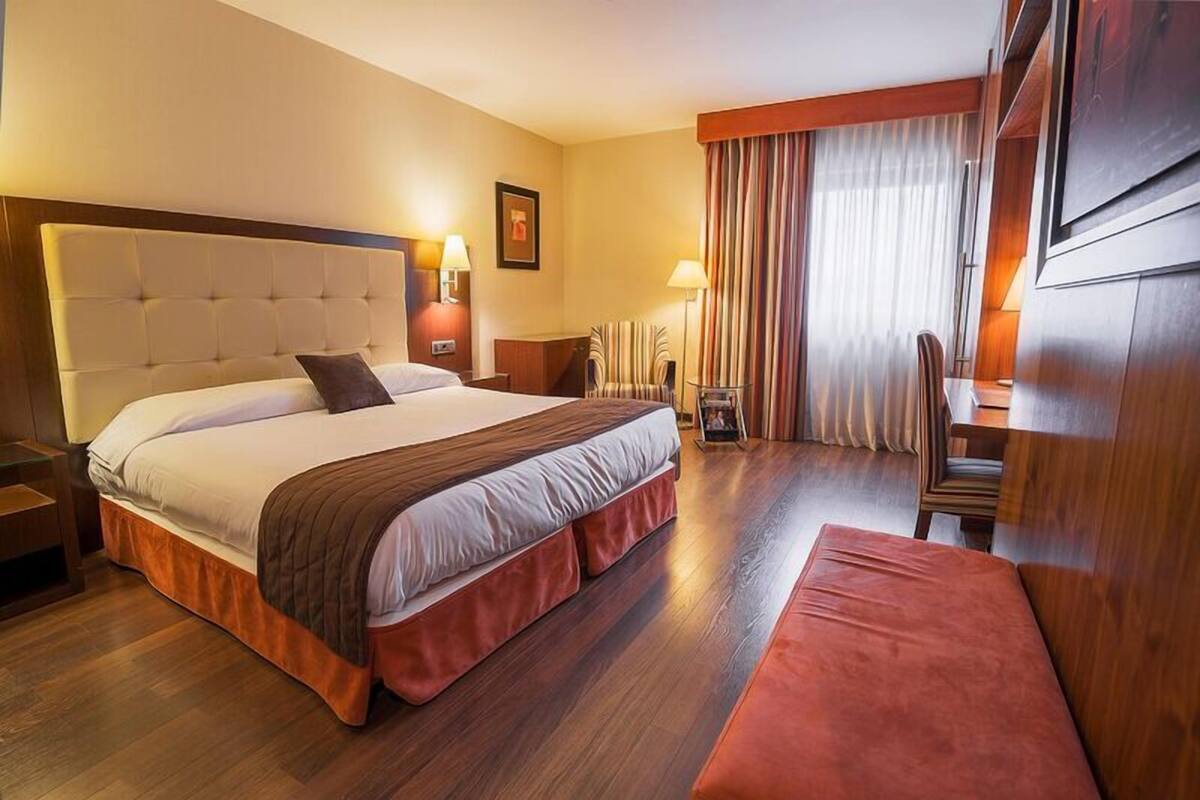 Une chambre d’hôtel avec un grand lit, un bureau et une chaise.
