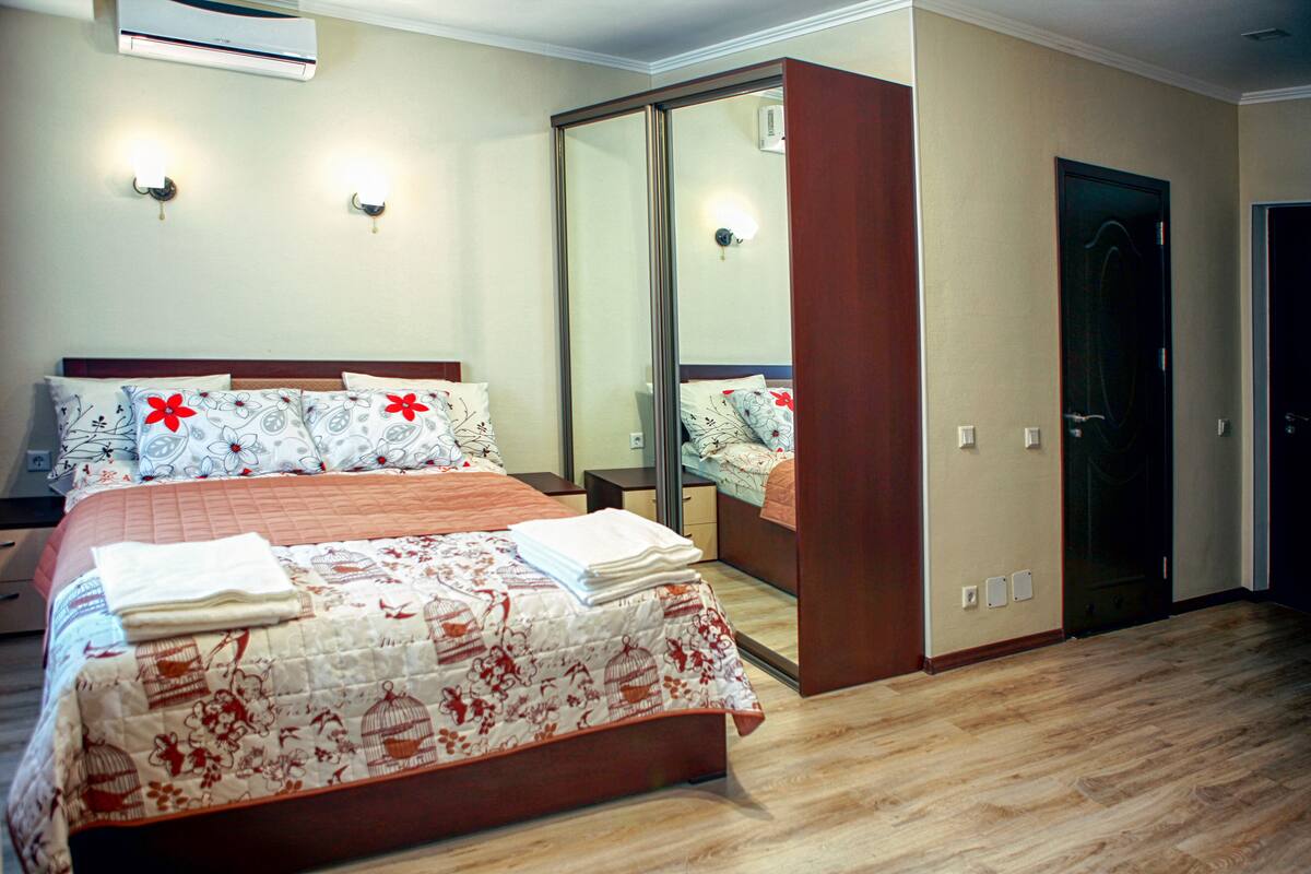 A hotel room with a large bed, a wardrobe, a mirror, and a door.