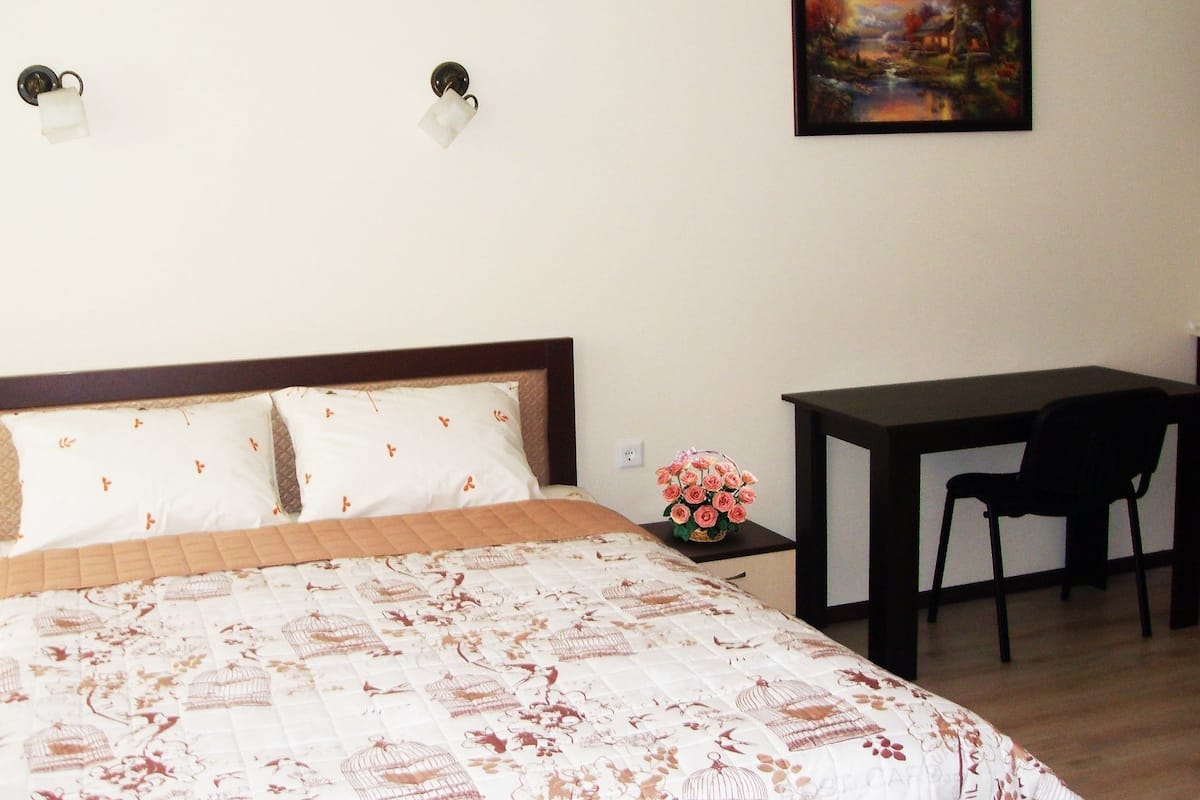 A neatly arranged bedroom with a bed, a desk, and a chair.