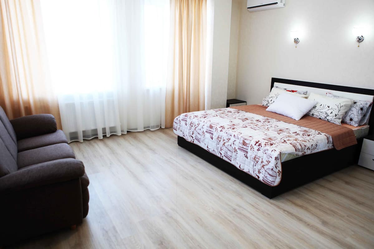 A bedroom with a bed, a chair, and a nightstand.