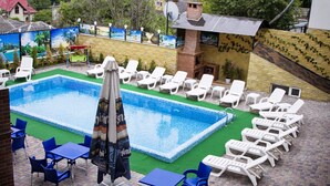 A swimming pool with lounge chairs and tables, surrounded by a brick patio and a mural wall. - Vila Lolo (Chisinau)