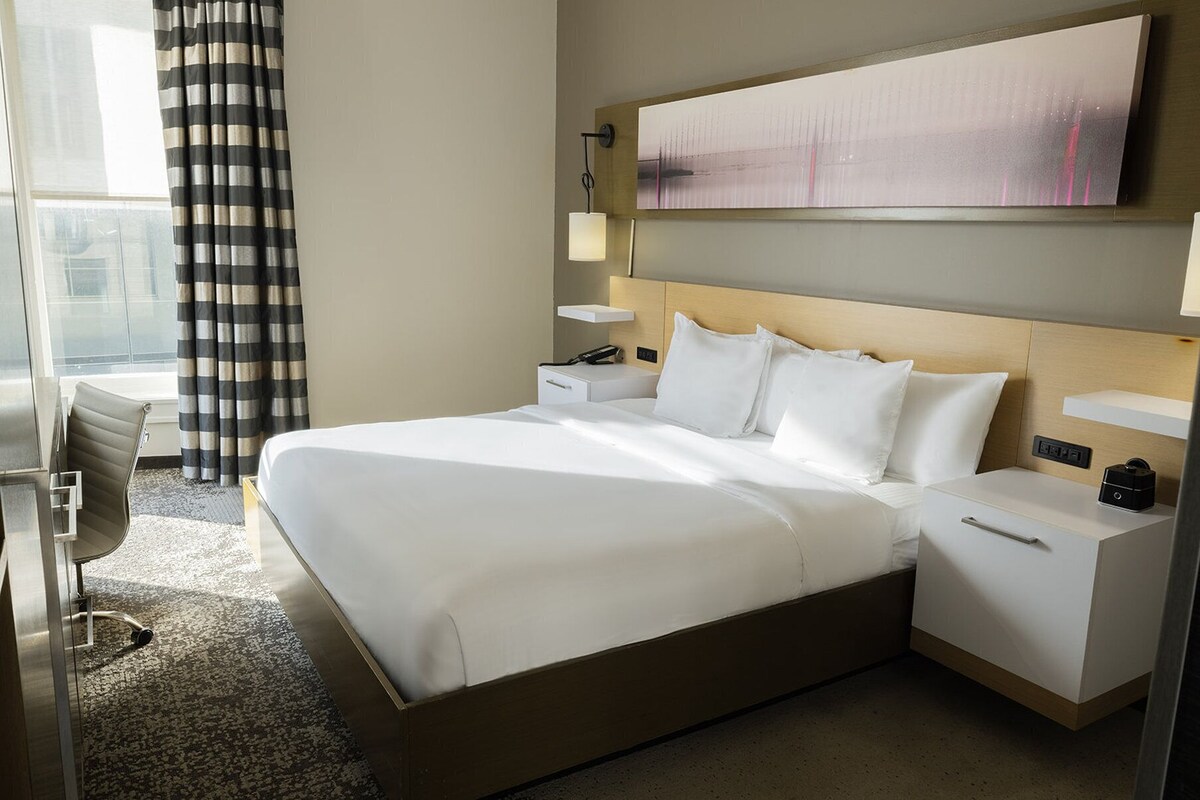 Une chambre d’hôtel avec un grand lit, des tables de chevet, un bureau et une chaise.