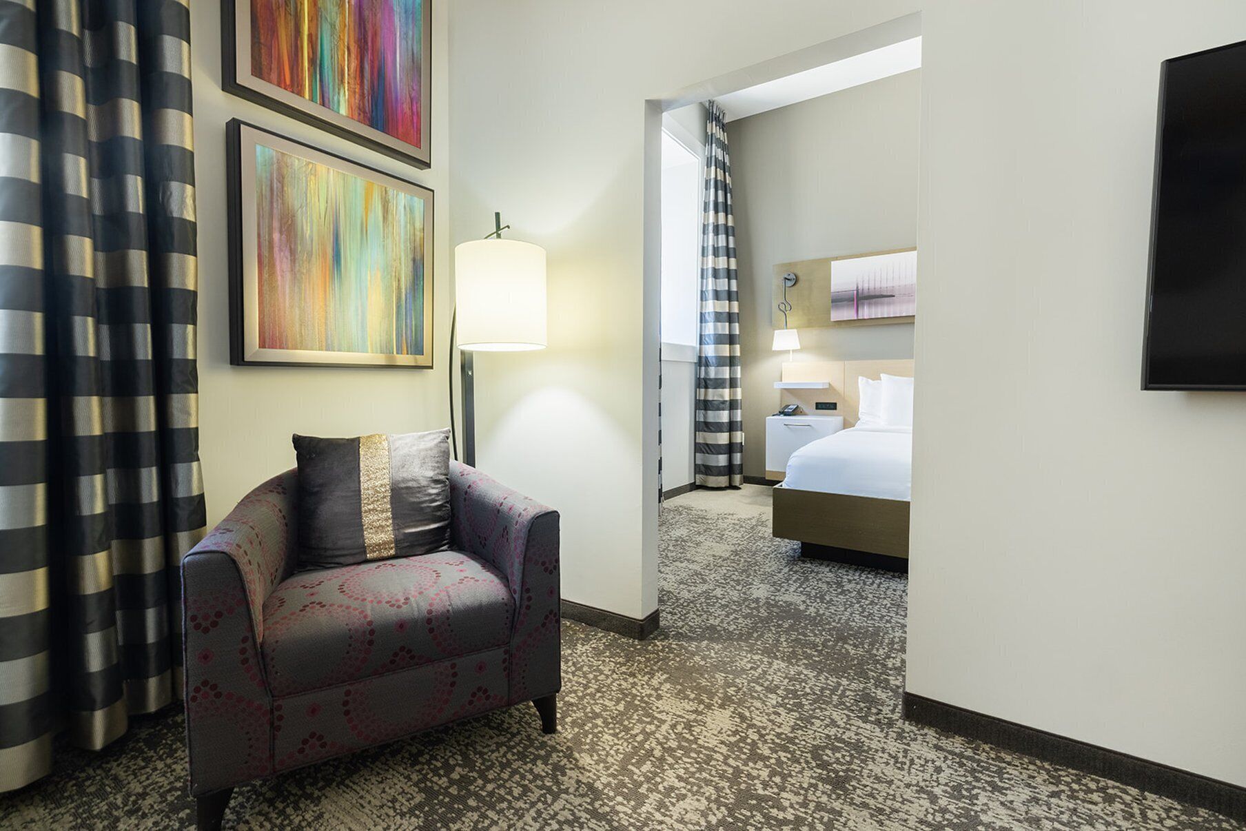 A hotel room with a sofa, a bed, a desk, and a TV.