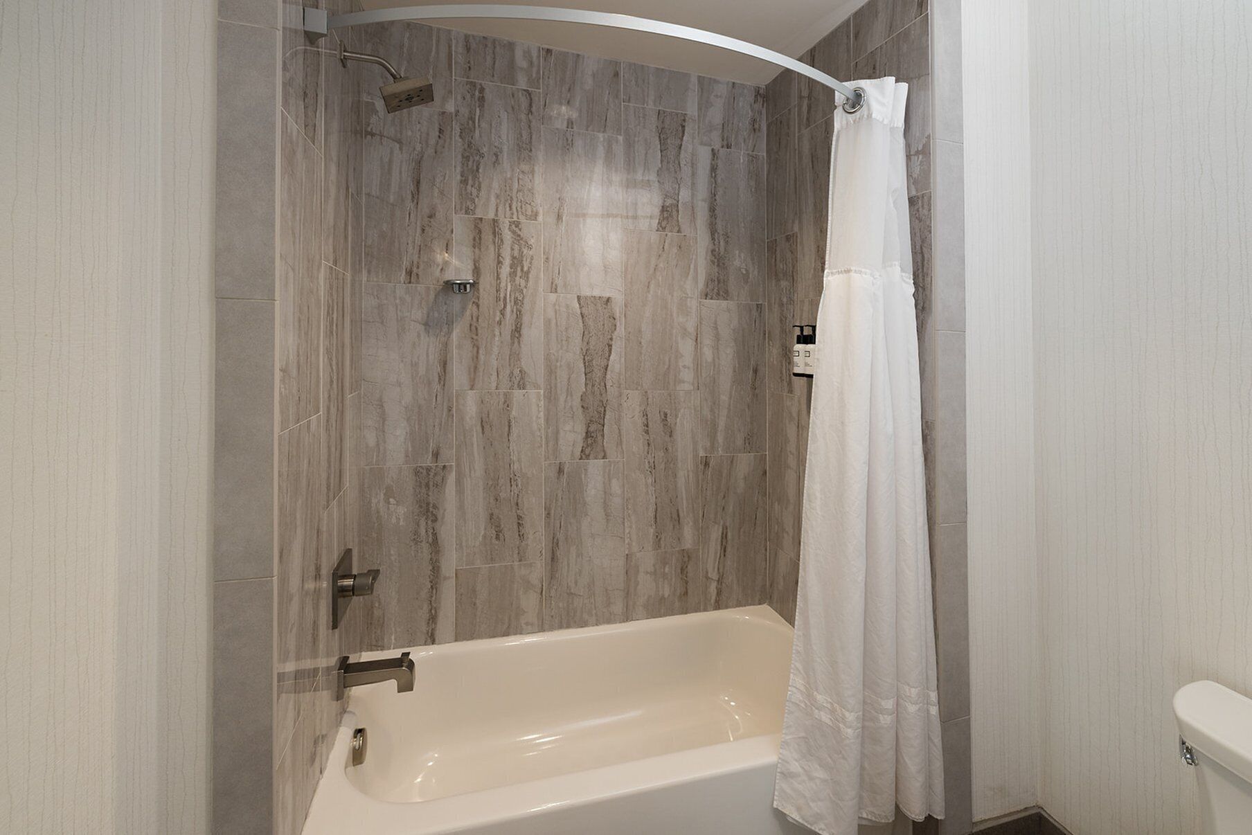 A modern bathroom with a bathtub, shower, and toilet.