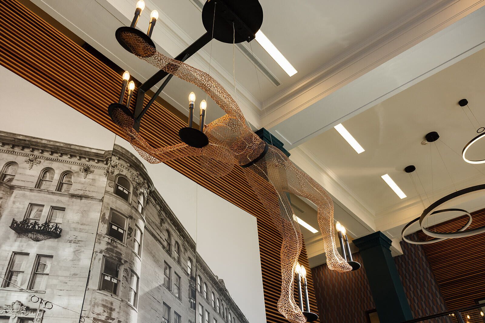 A modern interior with a unique hanging light fixture and a mural of an old building.