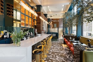 Eine moderne Bar mit einer langen Theke, mehreren Barhocker und einer Sitzgelegenheit mit Tischen und Stühlen.