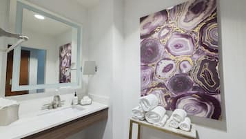 Een moderne badkamer met een wit wastafelmeubel, een grote spiegel en wanddecoratie met een marmerprint.