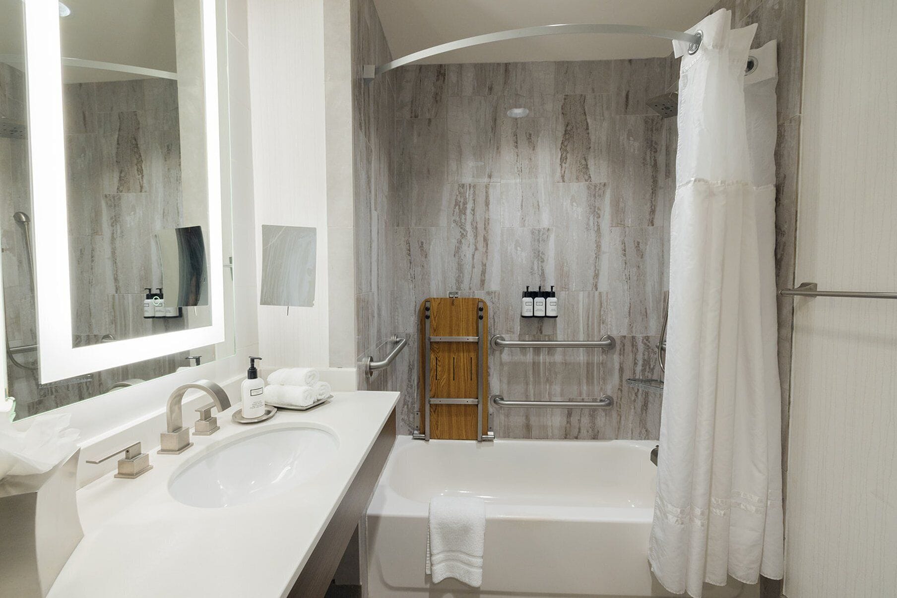 A modern bathroom with a white sink, vanity, and bathtub.