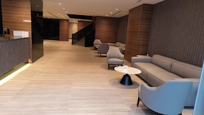 A modern lobby with a reception desk, seating area, and a staircase. - Manazil Aldiyaafa Company for Serviced Apartments (Riyadh)
