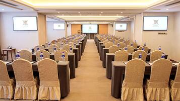 A conference room with rows of tables and chairs, each with a water bottle.