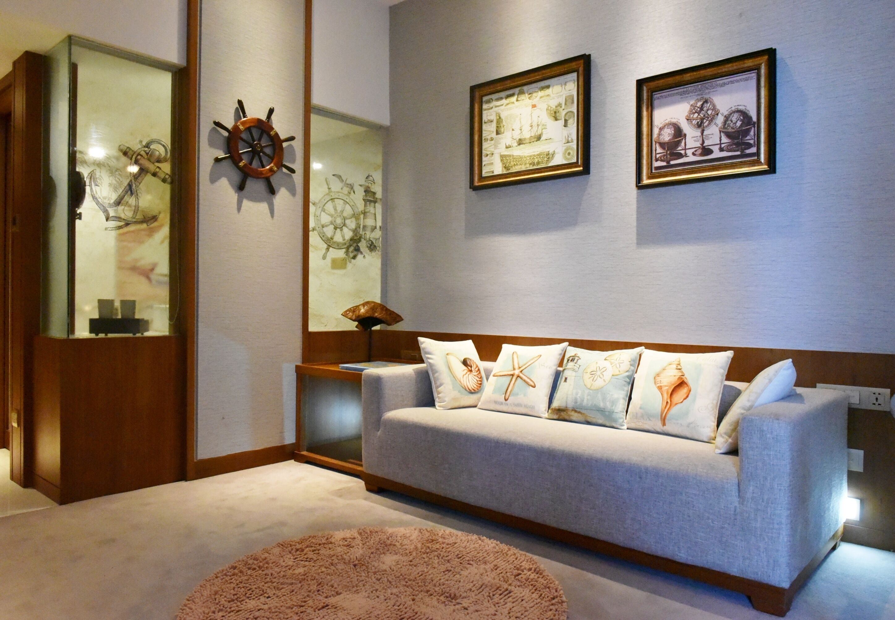 Ein Wohnzimmer mit einem hellgrauen Sofa, einem runden Teppich und Kissen im Seestil.