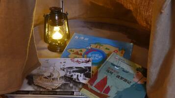 Un coin lecture confortable avec une lanterne, des livres et une maquette de bateau.