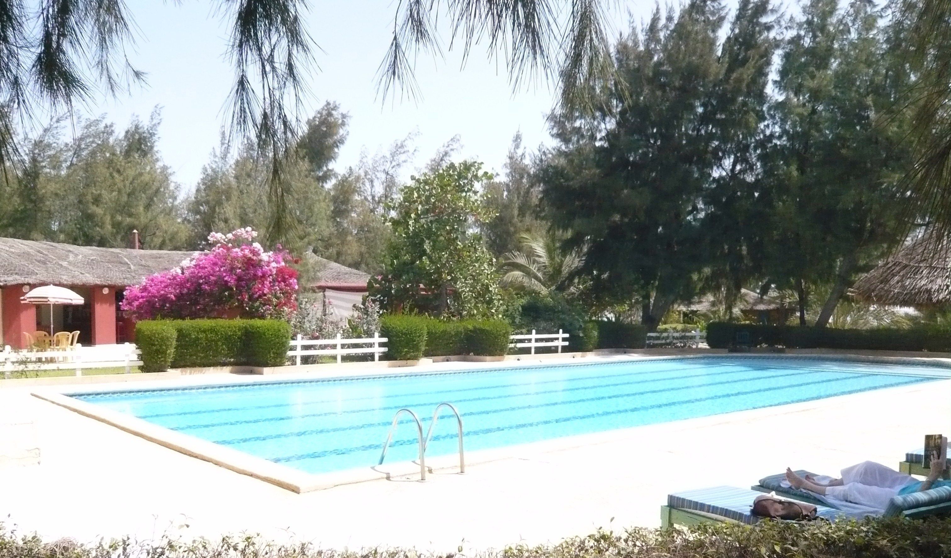 A swimming pool with lounge chairs and a thatched-roof building.