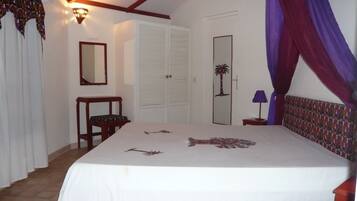 A bedroom with a bed, a nightstand, a chair, a wardrobe, and a door with a palm tree design.