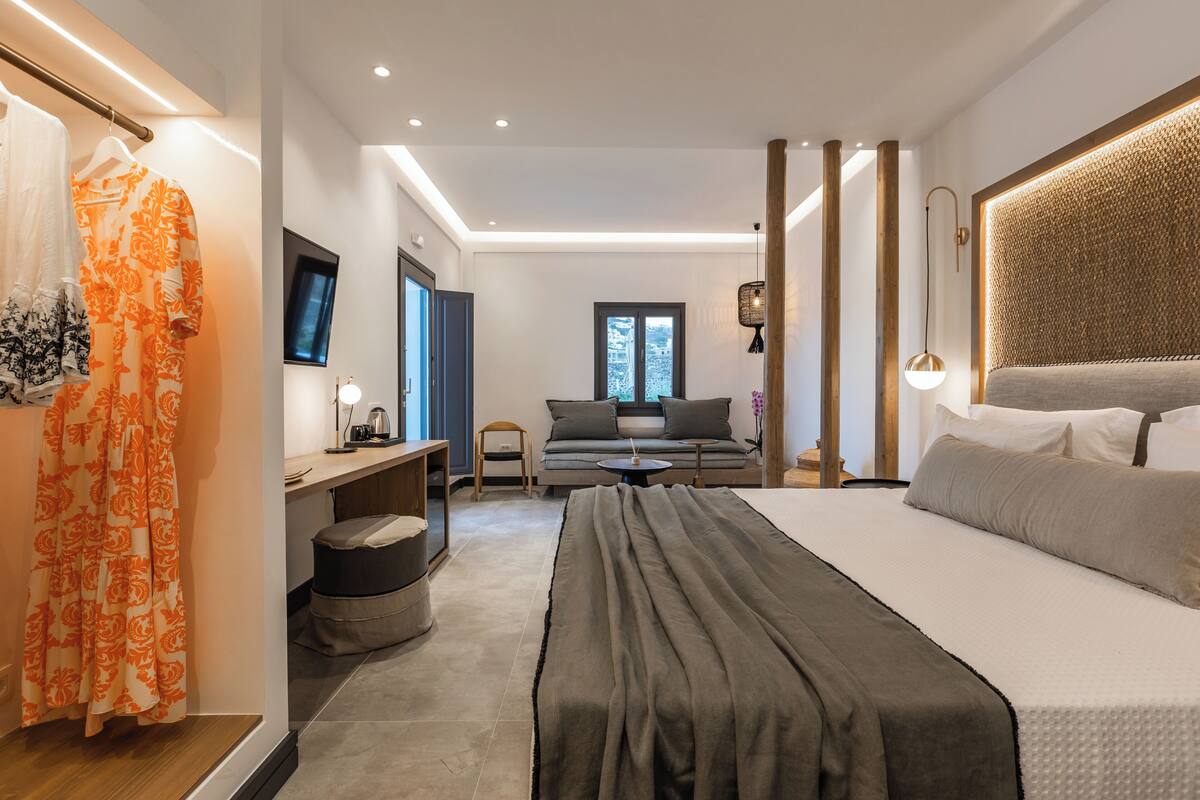 A modern bedroom with a large bed, a desk, and a sofa.