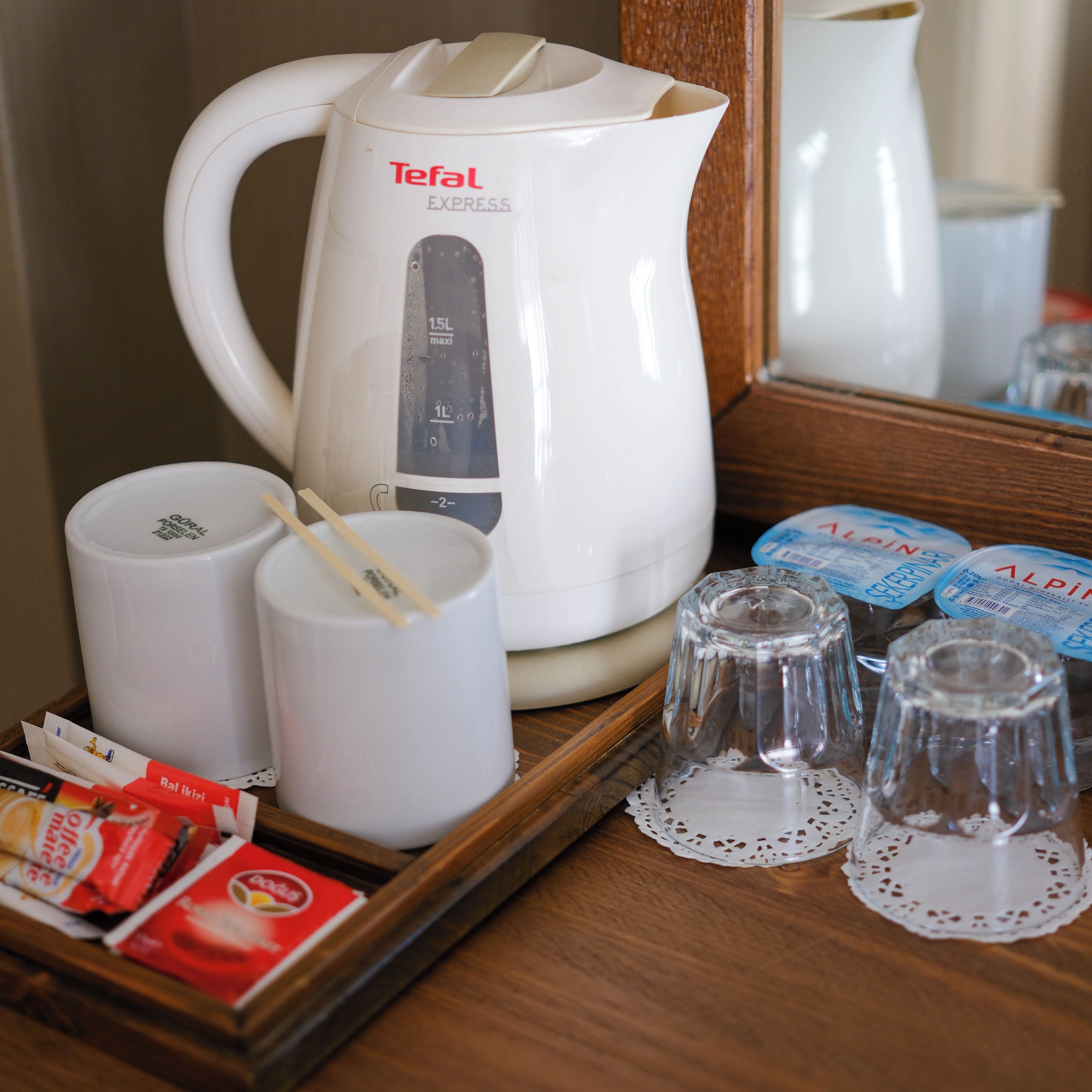 A kitchen area with a white Tefal Express kettle, two white mugs, and a tray with tea bags and a glass.