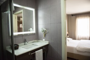 A modern bathroom with a sink, mirror, and towel rack. - Adana City Hotel (Adana)
