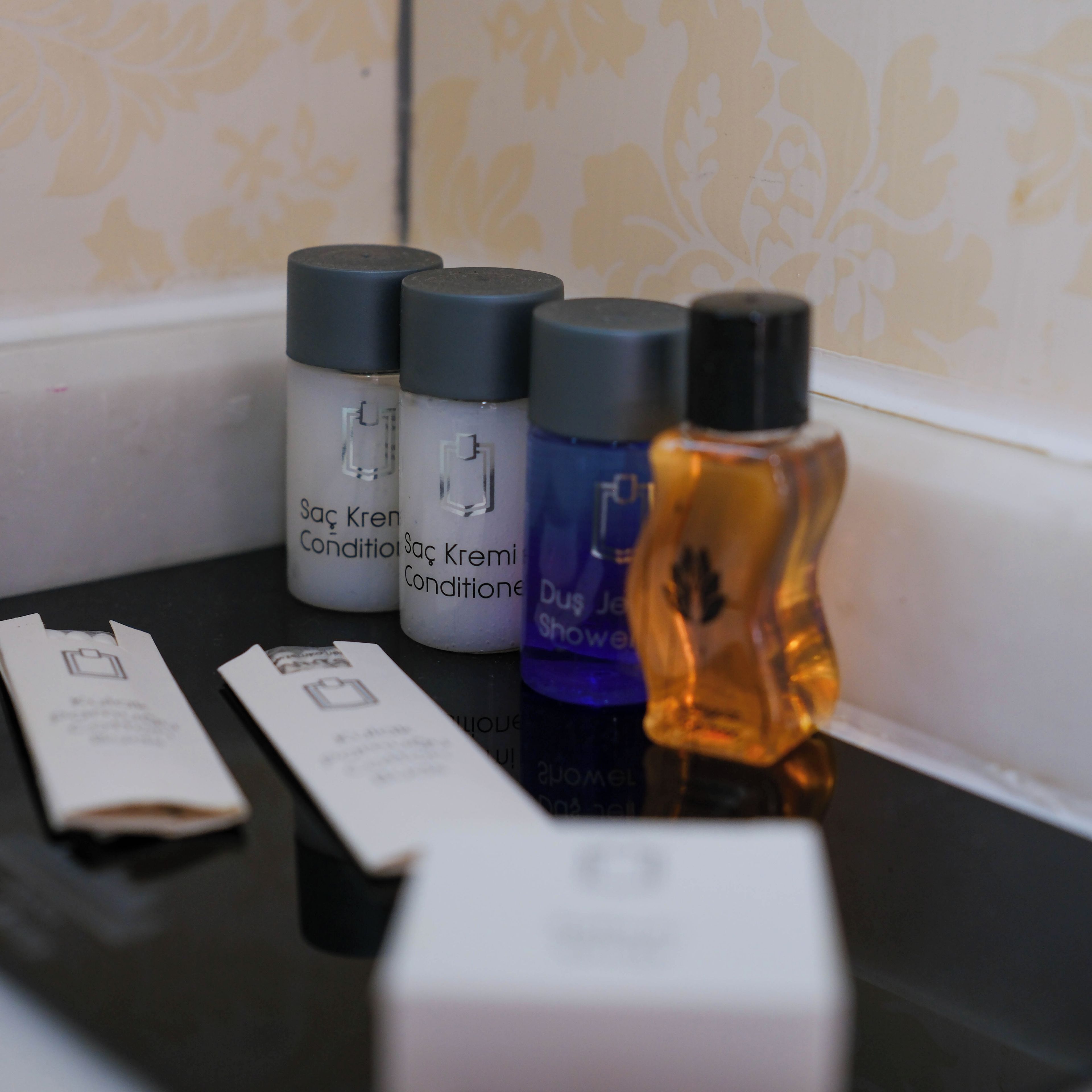 Una encimera de baño con artículos de aseo, incluyendo botellas de champú y acondicionador, una botella de loción y una pastilla de jabón.