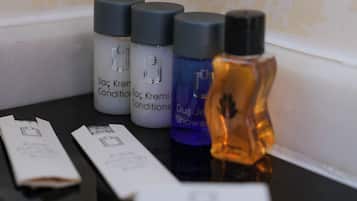 Una encimera de baño con artículos de aseo, incluyendo botellas de champú y acondicionador, una botella de loción y una pastilla de jabón.