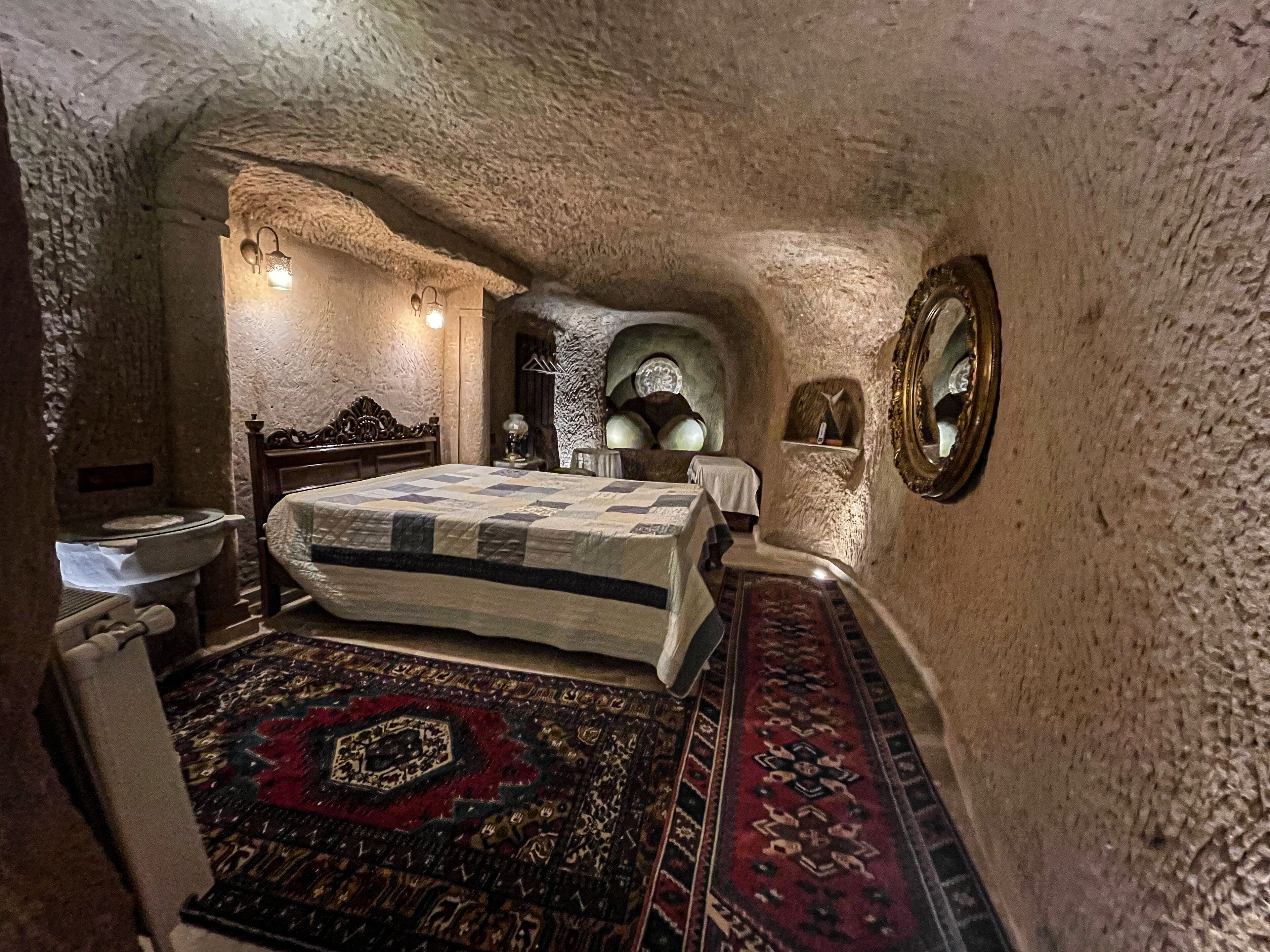 A room with a bed, a nightstand, a mirror, and a rug.