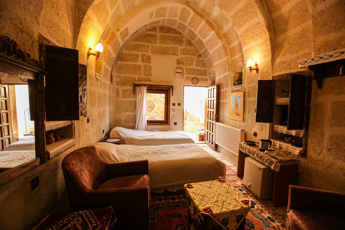 A traditional room with two beds, a small table, and a sofa.