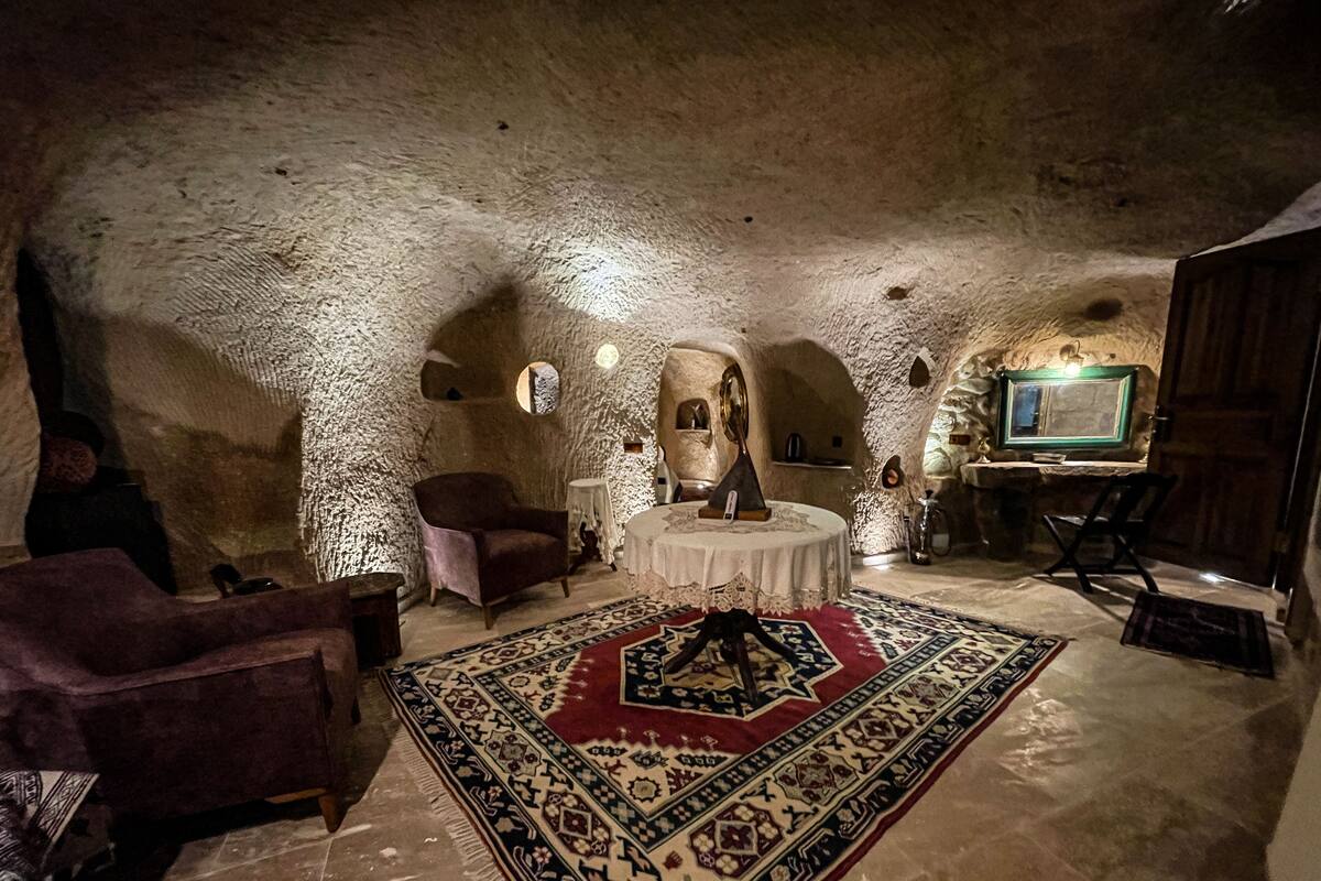 A cozy, rustic room with a round table, a patterned rug, and a comfortable chair.