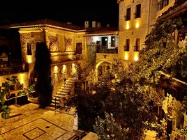 A courtyard with stone flooring, a staircase, and a building with balconies and ivy.